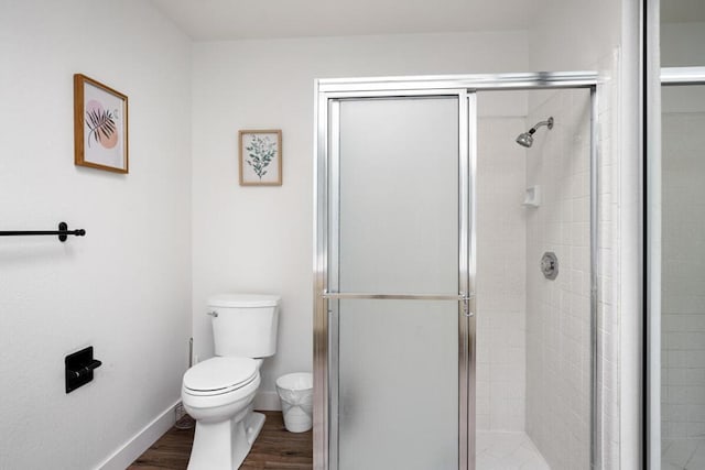 bathroom with hardwood / wood-style floors, toilet, and a shower with shower door