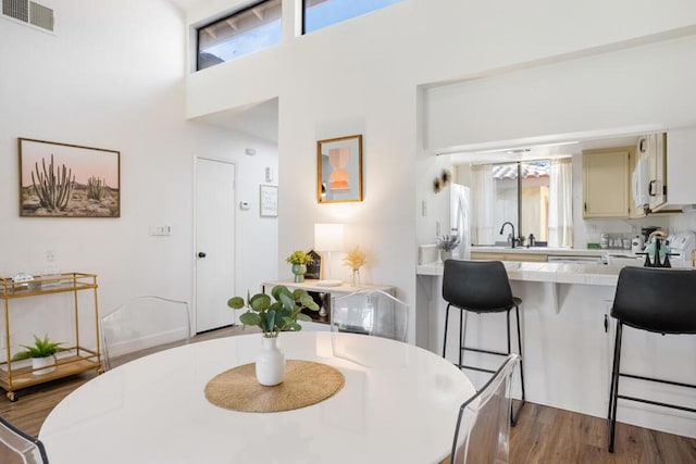 dining space featuring a high ceiling, light hardwood / wood-style floors, and sink