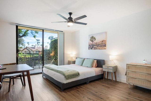 bedroom with ceiling fan, access to exterior, wood-type flooring, and a wall of windows