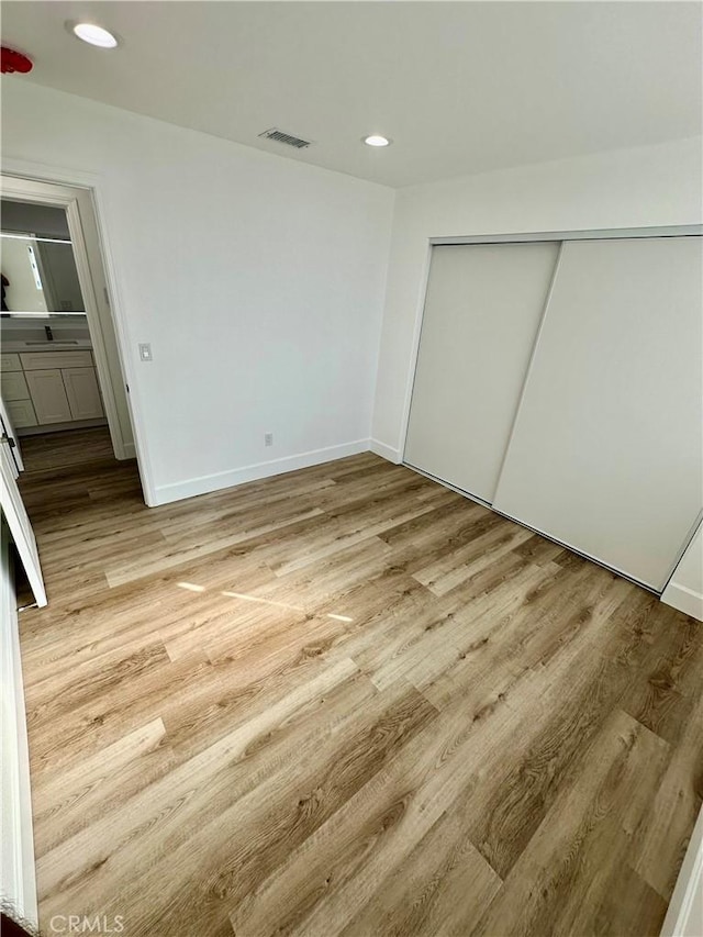 unfurnished bedroom with a closet and light hardwood / wood-style floors