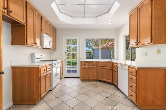 kitchen featuring a raised ceiling, white appliances, and light tile patterned floors