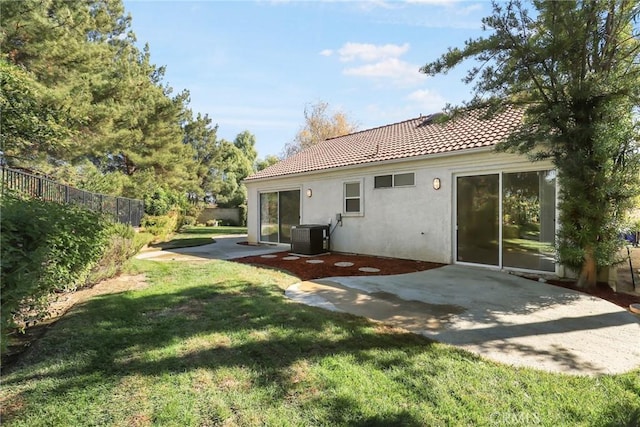 rear view of property with a lawn, a patio, and central AC