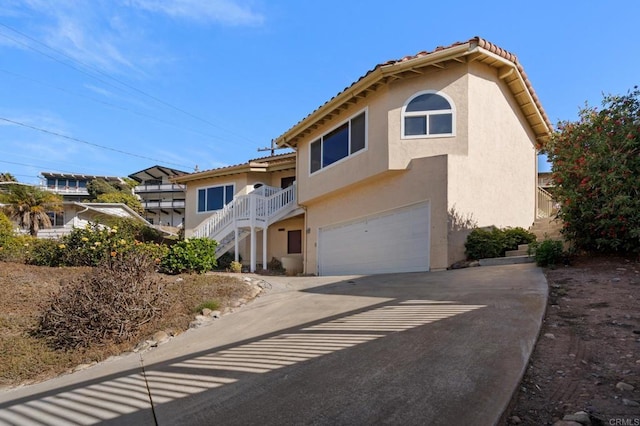 view of front of property featuring concrete driveway, an attached garage, a tile roof, and stucco siding