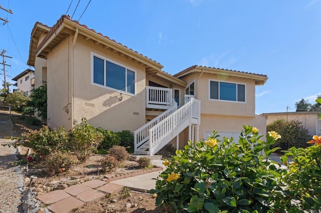 exterior space with a garage, stucco siding, a tiled roof, and stairs