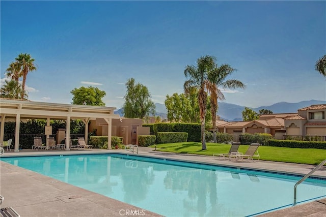 view of swimming pool featuring a patio area, a mountain view, and a yard