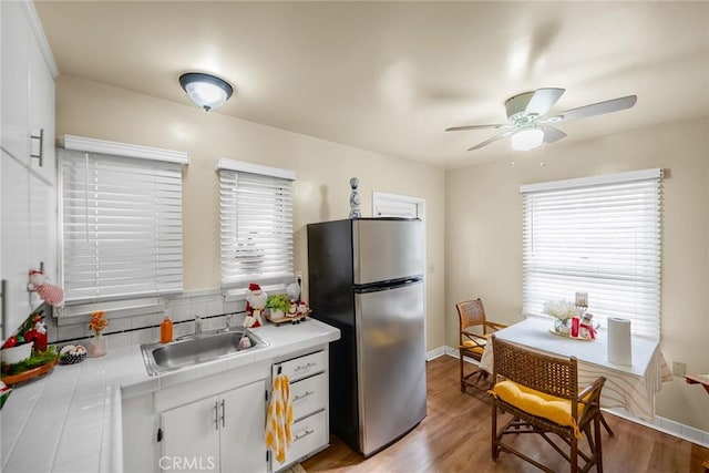 kitchen with stainless steel fridge, tasteful backsplash, sink, light hardwood / wood-style flooring, and white cabinets