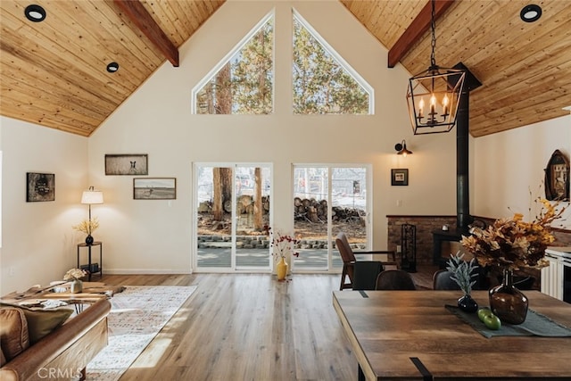 living room featuring hardwood / wood-style floors, high vaulted ceiling, a wood stove, and wooden ceiling