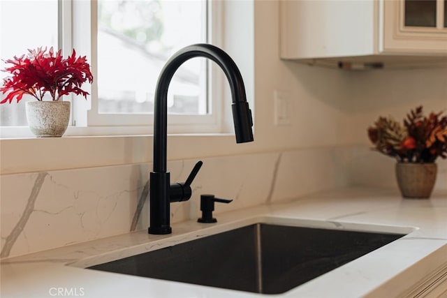 room details featuring light stone countertops, white cabinetry, and sink