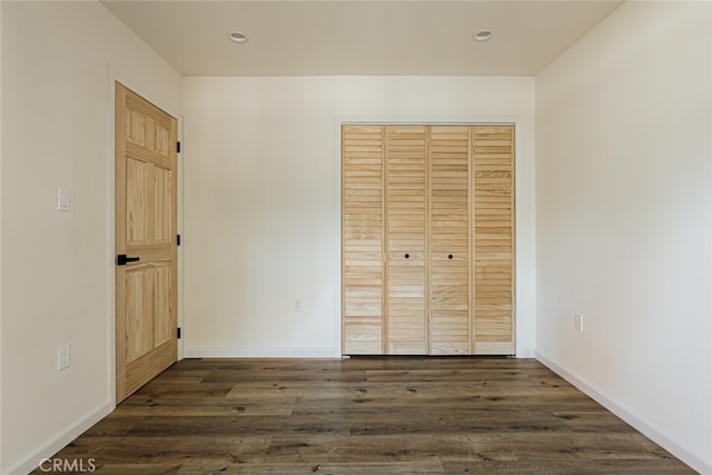 unfurnished bedroom with dark hardwood / wood-style flooring and a closet