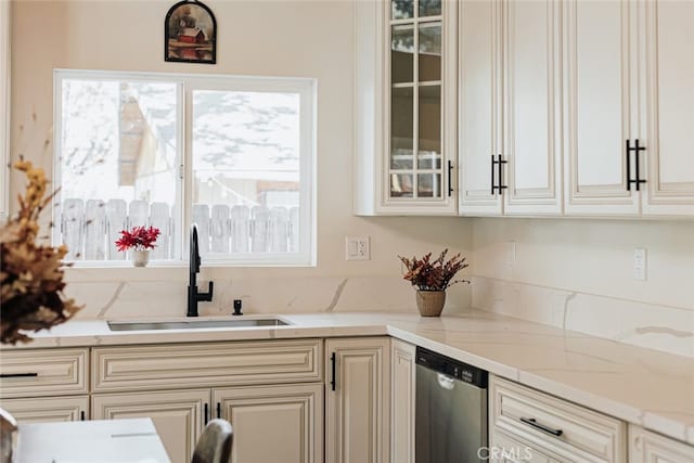 kitchen with cream cabinetry, dishwasher, light stone countertops, and sink