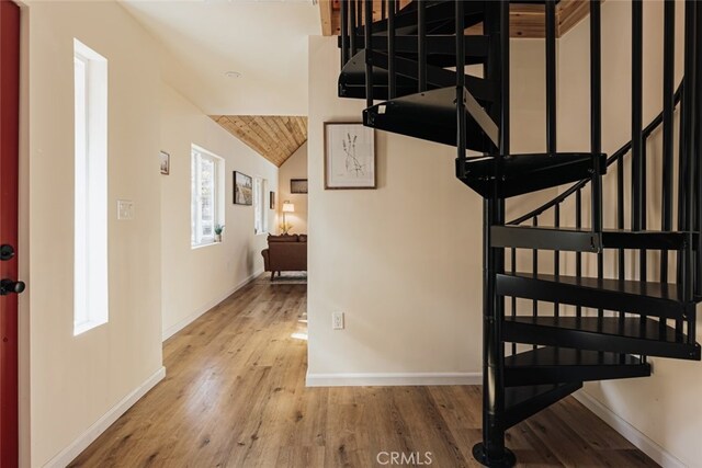 staircase with wood-type flooring and vaulted ceiling