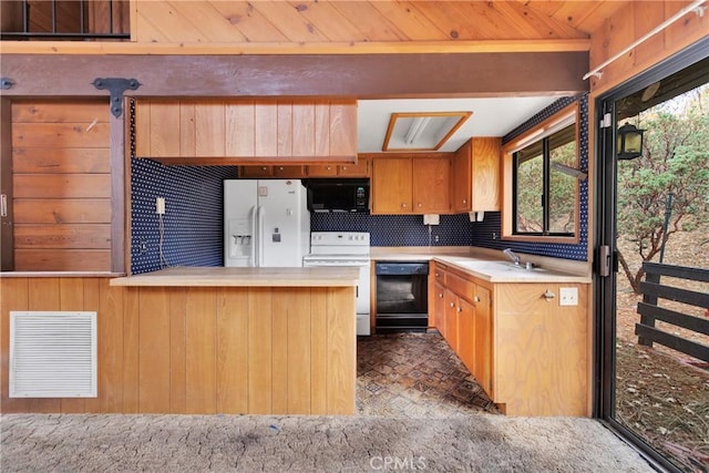 kitchen with sink, kitchen peninsula, wood walls, decorative backsplash, and black appliances