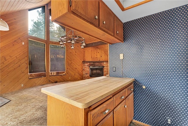 kitchen with a fireplace, carpet, kitchen peninsula, and wood walls