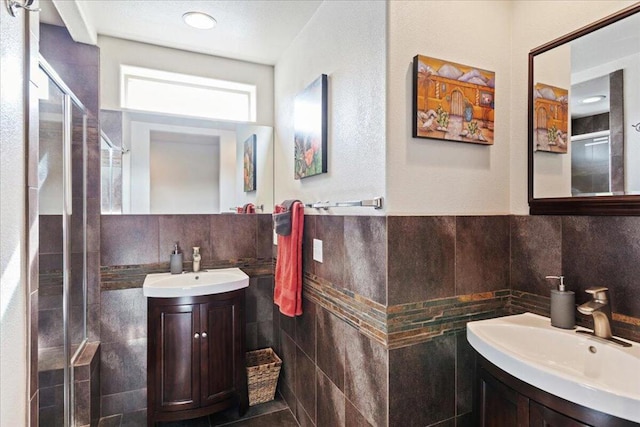 bathroom featuring vanity, a shower with shower door, and tile walls