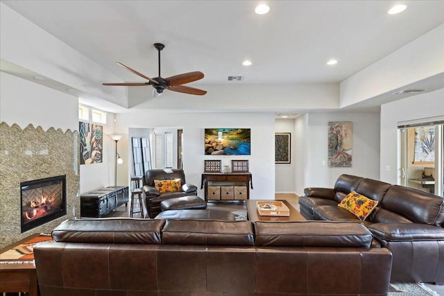 living room with ceiling fan and a high end fireplace