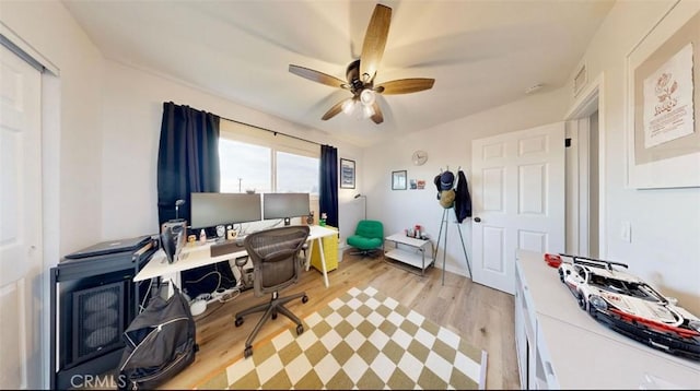 office with light wood-type flooring and ceiling fan