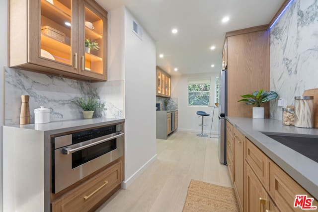 kitchen with stainless steel appliances, light hardwood / wood-style floors, and decorative backsplash