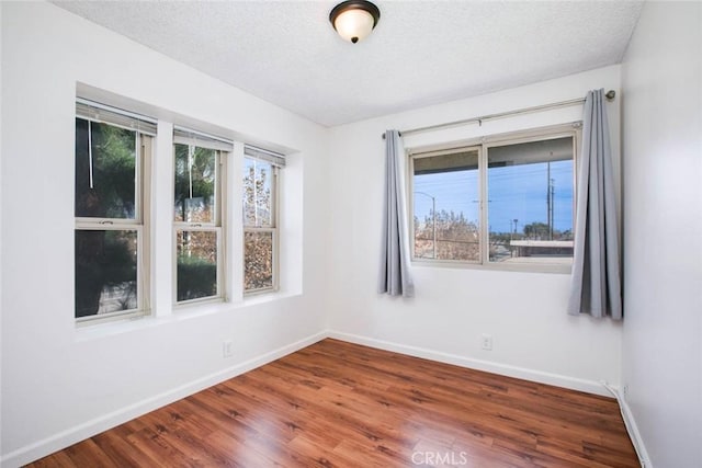 unfurnished room with wood-type flooring and a textured ceiling