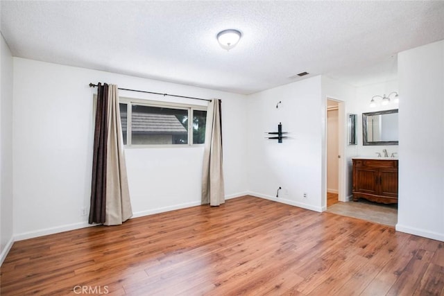 spare room featuring hardwood / wood-style floors, a textured ceiling, and sink