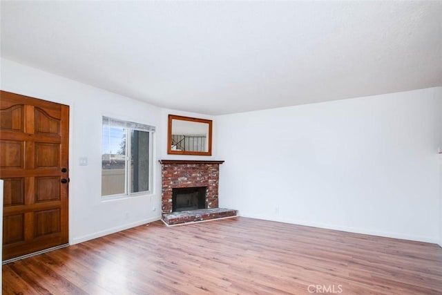 unfurnished living room with hardwood / wood-style flooring and a brick fireplace