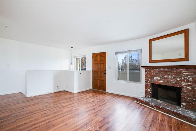 unfurnished living room with hardwood / wood-style flooring and a brick fireplace