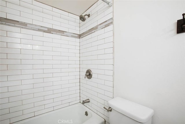 bathroom with tiled shower / bath combo and toilet