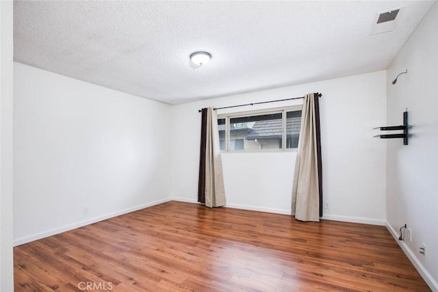 spare room featuring hardwood / wood-style floors and a textured ceiling