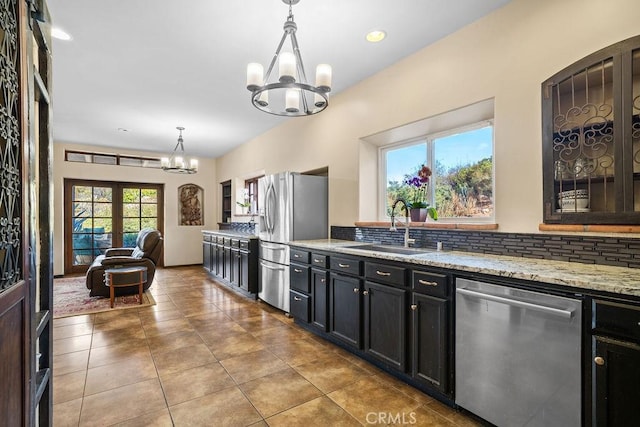 kitchen with appliances with stainless steel finishes, decorative light fixtures, french doors, a chandelier, and sink