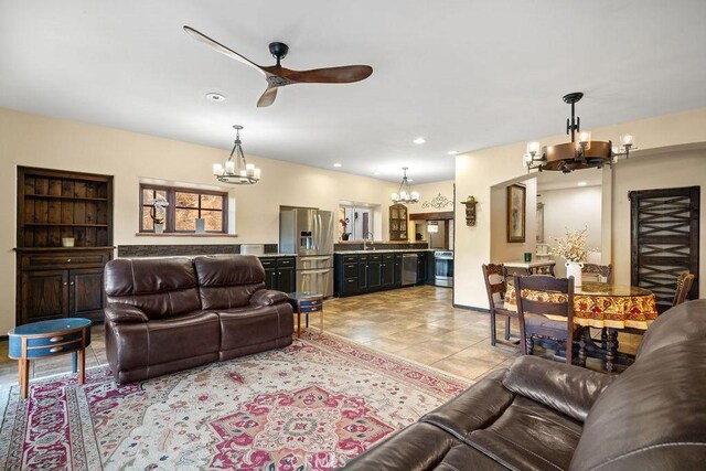 tiled living room featuring ceiling fan with notable chandelier, sink, and built in shelves