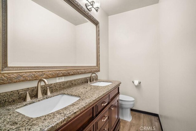 bathroom with hardwood / wood-style floors, toilet, and vanity