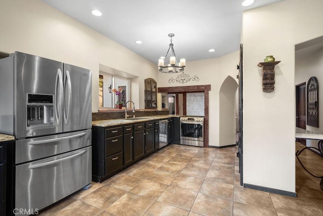 kitchen featuring light stone countertops, sink, appliances with stainless steel finishes, and a chandelier