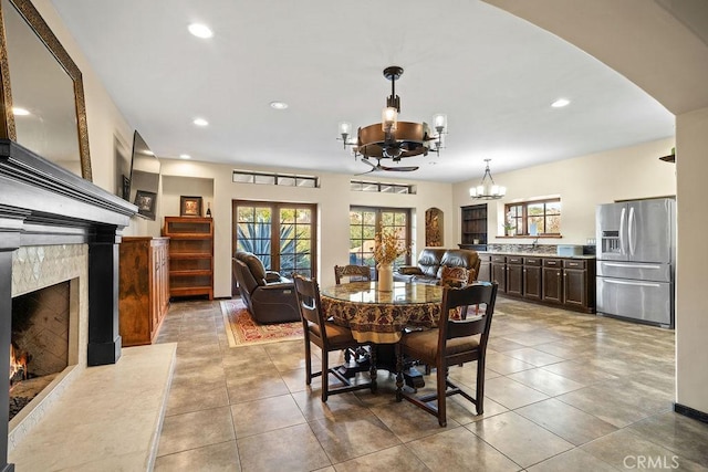 tiled dining area featuring a fireplace and an inviting chandelier