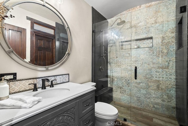 bathroom featuring toilet, vanity, and a shower with door