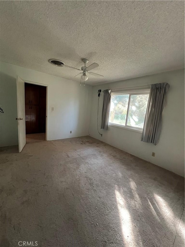 unfurnished bedroom with ceiling fan, carpet floors, a textured ceiling, and a closet