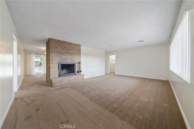 unfurnished living room with a textured ceiling, a fireplace, and light carpet