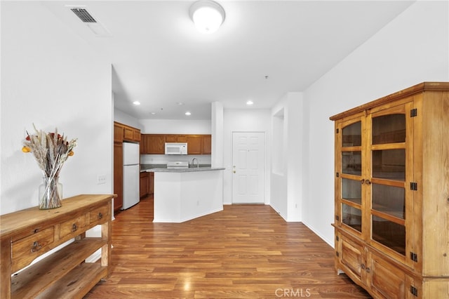 kitchen featuring sink, wood-type flooring, and white appliances