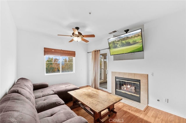 living room featuring ceiling fan, a fireplace, and light wood-type flooring