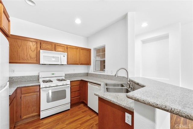 kitchen featuring kitchen peninsula, light stone countertops, light wood-type flooring, white appliances, and sink