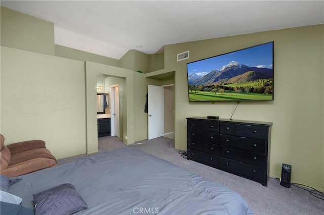 bedroom featuring ensuite bath, light carpet, and lofted ceiling