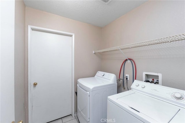 laundry room with light tile patterned floors, a textured ceiling, and independent washer and dryer