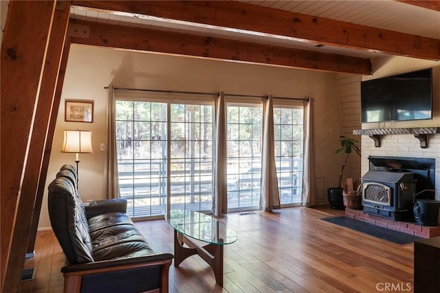 living room featuring hardwood / wood-style floors, a wood stove, beamed ceiling, and wood ceiling