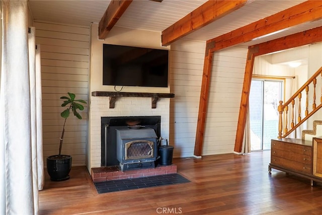 living room featuring wood-type flooring, a wood stove, wooden walls, and beam ceiling