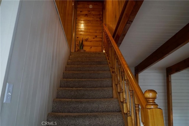 stairway with beam ceiling and wooden walls