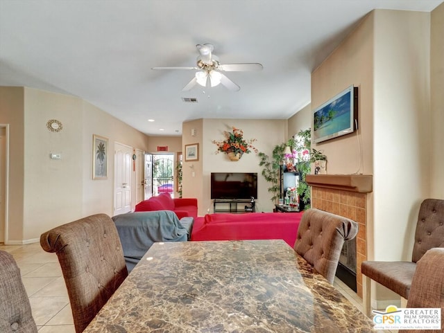 dining space with ceiling fan, light tile patterned floors, and a tiled fireplace