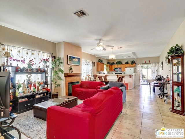 tiled living room with ceiling fan and a fireplace