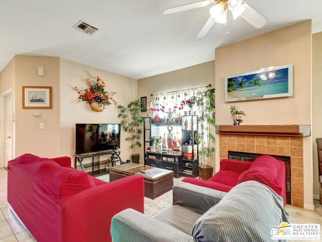 tiled living room with a tile fireplace and ceiling fan