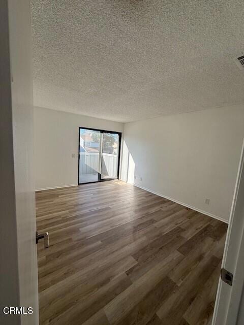 empty room with dark wood-type flooring and a textured ceiling