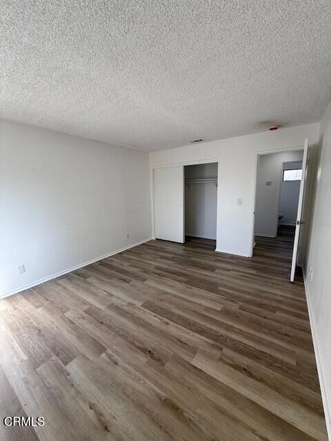 unfurnished bedroom with dark hardwood / wood-style flooring, a closet, and a textured ceiling