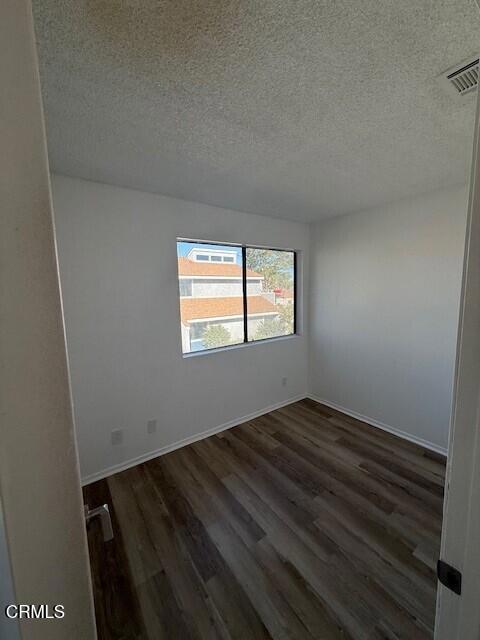 spare room featuring dark wood-type flooring and a textured ceiling