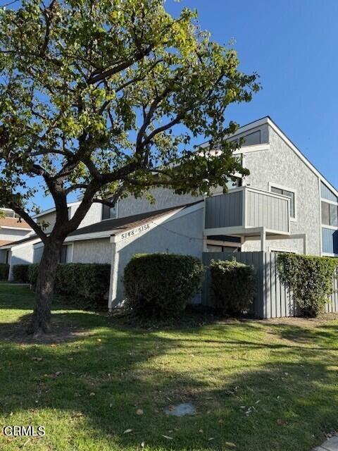 view of property exterior with a yard and a balcony